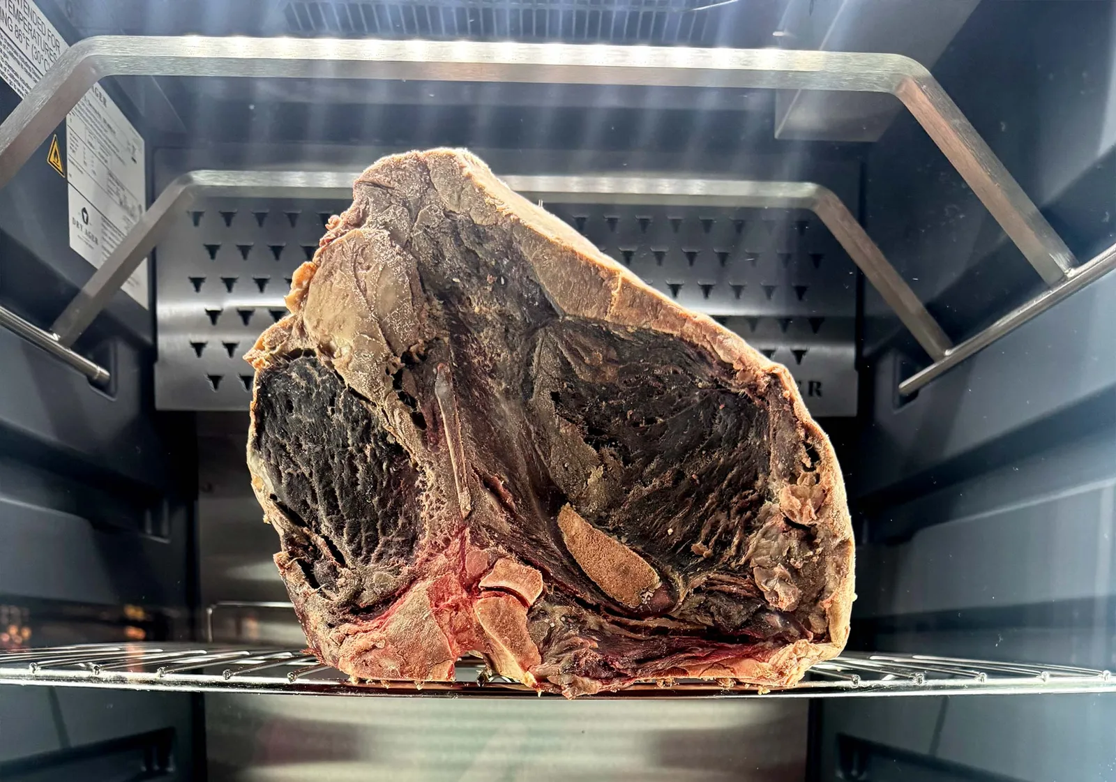 USDA Prime short loin dry-aging on a rack at Farm Country Meats in Union, Missouri.