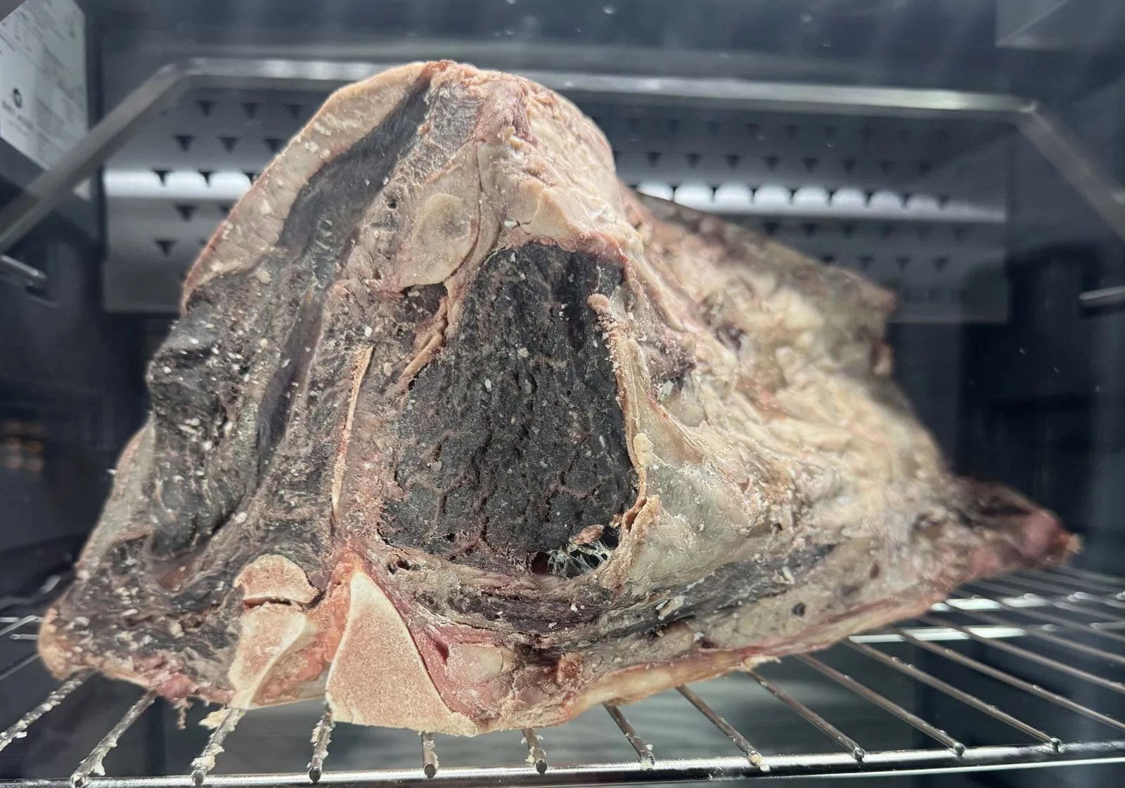 USDA Prime short loin dry-aging on a rack at Farm Country Meats in Union, Missouri.