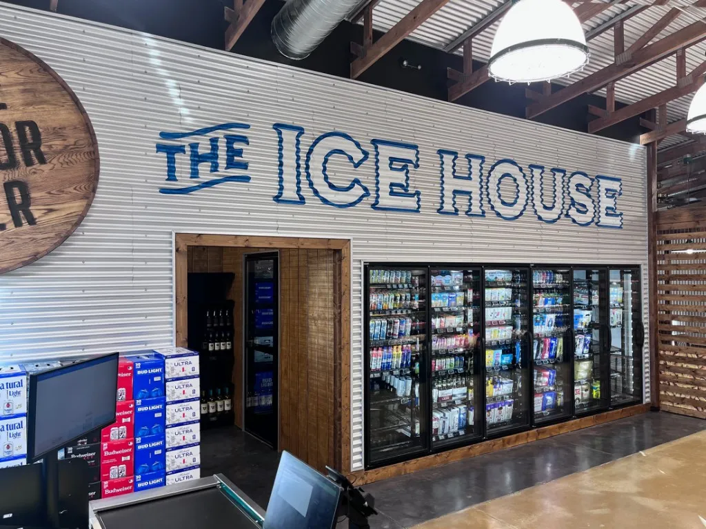 The Icehouse at Farm Country Meats & Market in Union, Missouri, with a glass-door cooler, stacked beer cases, and blue wall lettering.